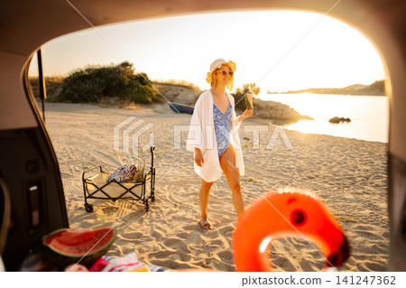 Woman enjoying summer beach vacation eating watermelon at sunset Woman enjoying summer beach vacation eating watermelon at sunset 141247362