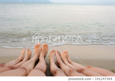 Family feet relaxing in sand by ocean waves on vacation in Greece Family feet relaxing in sand by ocean waves on vacation in Greece 141247364