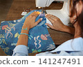 A girl sews on a sewing machine 141247491