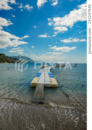 Floating Pier with Boats and Jet Skis in Turquoise Sea Near Mountains Floating Pier with Boats and Jet Skis in Turquoise Sea Near Mountains 141247640