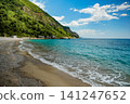 Turquoise Sea Wave Washing Sandy Beach Below Green Mountain 141247652
