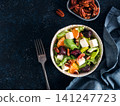 Healthy winter salad with beet cubes, feta cheese, orange segments and pecans in bowl. Flat lay on dark textured background with copy space. Perfect for restaurant menu or organic diet blog. Top view 141247723