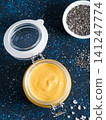 Homemade plant-based chia cheeze sauce for snacks, tacos and nachos. Creamy dairy-free dip on dark background with copy space. Vertical. Creamy Cheddar sauce with chia seeds on dark blue background 141247774