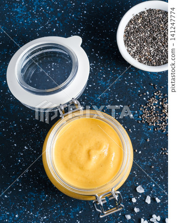 Homemade plant-based chia cheeze sauce for snacks, tacos and nachos. Creamy dairy-free dip on dark background with copy space. Vertical. Creamy Cheddar sauce with chia seeds on dark blue background Homemade plant-based chia cheeze sauce for snacks, tacos and nachos. Creamy dairy-free dip on dark background with copy space. Vertical. Creamy Cheddar sauce with chia seeds on dark blue background 141247774