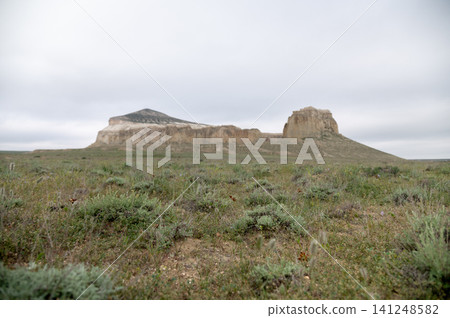 Rocky outcrop with grassy plains under overcast sky in remote landscape Rocky outcrop with grassy plains under overcast sky in remote landscape 141248582
