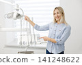Dentist adjusting dental light and pointing at control panel 141248622
