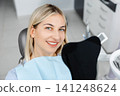 Smiling patient sitting in dentist chair showing perfect teeth 141248624