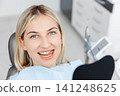 Smiling patient sitting in dentist chair showing perfect teeth 141248625