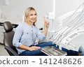 Young woman pointing up during dental checkup showing confidence in her oral health 141248626