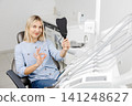 Patient showing ok sign while holding dental mirror at clinic 141248627