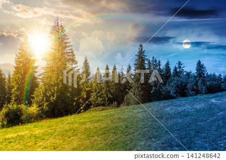 landscape with coniferous forest in summer. day meet night. scenic view of mountain landscape in poland. sun and moon in harmony over spruce trees on a grassy alpine meadow. epic sky above the ridge landscape with coniferous forest in summer. day meet night. scenic view of mountain landscape in poland. sun and moon in harmony over spruce trees on a grassy alpine meadow. epic sky above the ridge 141248642