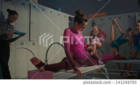 Focused Rhythmic Gymnast Performing Deep Over split Stretching on Bench Focused Rhythmic Gymnast Performing Deep Over split Stretching on Bench 141248793
