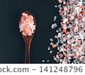 Coarse pink himalayan salt crystals in a dark wooden spoon and scattered on black slate stone background. Top view flat lay composition with copy space. Perfect for cooking, spa or wellness concept 141248796
