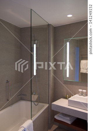 Wroclaw, Poland, June 15, 2018: Bathtub and shower with glass splash guard in luxury hotel bathroom Wroclaw, Poland, June 15, 2018: Bathtub and shower with glass splash guard in luxury hotel bathroom 141249152