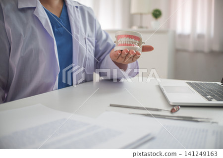 Close-up hand of Female Dentist working in office. Holding denture model. Close-up hand of Female Dentist working in office. Holding denture model. 141249163