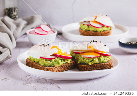 Sandwiches with avocado, radish and poached egg on a plate on the table 141249326
