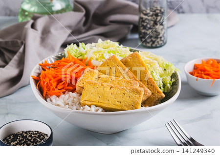 A bowl of rice with fried tofu, Chinese cabbage and carrots on the table A bowl of rice with fried tofu, Chinese cabbage and carrots on the table 141249340