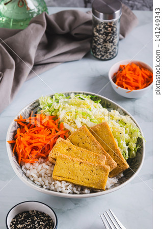 A small portion of rice with grilled tofu, Chinese cabbage and carrots in a bowl on the table vertical view A small portion of rice with grilled tofu, Chinese cabbage and carrots in a bowl on the table vertical view 141249343