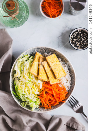 A small portion of rice with grilled tofu, Chinese cabbage and carrots in a bowl top and vertical view A small portion of rice with grilled tofu, Chinese cabbage and carrots in a bowl top and vertical view 141249346
