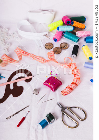 Sewing thread, measuring tape, pattern, and sewing accessories on the white fabric vertical view Sewing thread, measuring tape, pattern, and sewing accessories on the white fabric vertical view 141249352