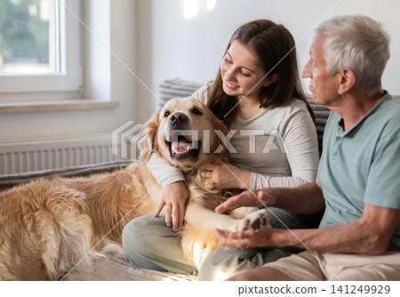 Happy Girl With Grandfather Playing With Golden Retriever Dog Sitting On A Sofa Happy Girl With Grandfather Playing With Golden Retriever Dog Sitting On A Sofa 141249929