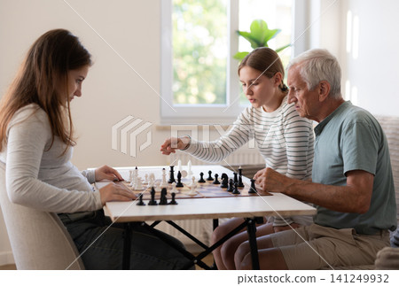Grandfather Playing Chess With Granddaughters And Teaching Girls The Rules Grandfather Playing Chess With Granddaughters And Teaching Girls The Rules 141249932
