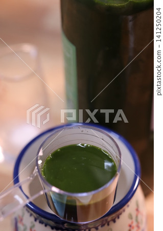 Green Liquid Pouring into Measuring Cup Green Liquid Pouring into Measuring Cup 141250204