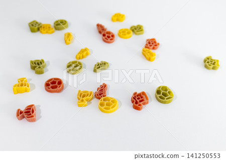 Colorful pasta pieces with football themed shapes scattered on a white surface, creating playful football themed food art. Colorful pasta pieces with football themed shapes scattered on a white surface, creating playful football themed food art. 141250553