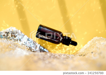 Dropper bottle serum skincare product shimmering on sequins Dropper bottle serum skincare product shimmering on sequins 141250780