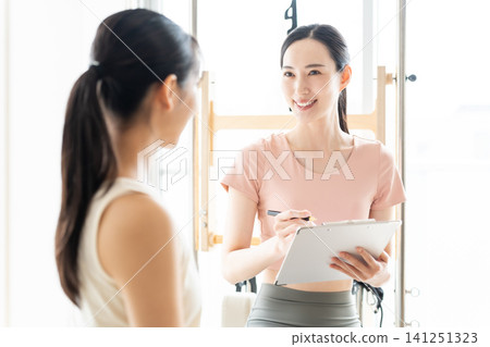 一位女士正在聽普拉提工作室的講解 一位女士正在聽普拉提工作室的講解 141251323