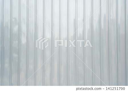Close-up of a light gray corrugated metal sheet with vertical ridges. Industrial texture background with soft lighting and reflections. Perfect for architectural and construction themes. Close-up of a light gray corrugated metal sheet with vertical ridges. Industrial texture background with soft lighting and reflections. Perfect for architectural and construction themes. 141251700