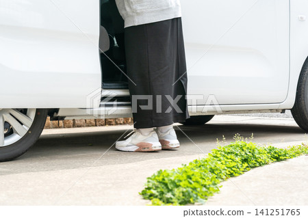 The feet and sneakers of a woman standing in front of the sliding door of a white minicar The feet and sneakers of a woman standing in front of the sliding door of a white minicar 141251765