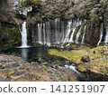 A beautiful waterfall and clear stream cascading down a rocky cliff face. 141251907