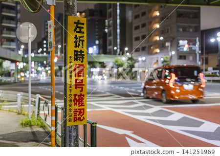 A warning sign posted at an intersection at night reminding people to check the traffic signal before turning left. A warning sign posted at an intersection at night reminding people to check the traffic signal before turning left. 141251969