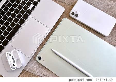 A modern desk with a laptop and smart devices side by side. A modern desk with a laptop and smart devices side by side. 141251992