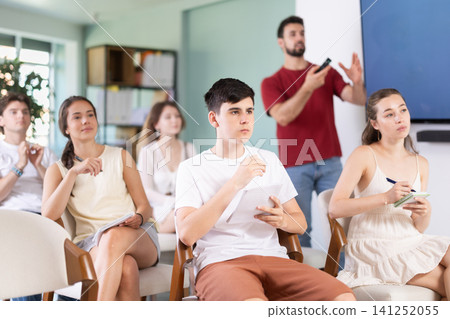 Group of students listening to lecture with teacher in background Group of students listening to lecture with teacher in background 141252055