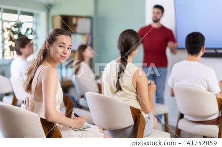 woman sits at a lecture in front of a talking teacher woman sits at a lecture in front of a talking teacher 141252059