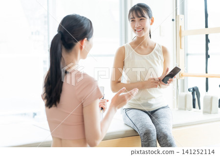A woman shows her smartphone in a Pilates studio. A woman shows her smartphone in a Pilates studio. 141252114