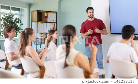teacher stands near a screen and gives a lecture to students teacher stands near a screen and gives a lecture to students 141252135