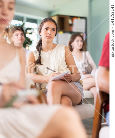 Young woman listening to lecture in group classroom 141252141