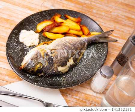 Whole baked dorado fish with potato on plate Whole baked dorado fish with potato on plate 141252151