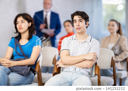 Young students sit in the auditorium and listen to a lecture Young students sit in the auditorium and listen to a lecture 141252212