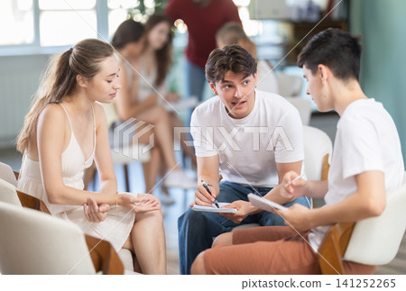 Two teams of young men and women sit in the auditorium, they communicate and discuss Two teams of young men and women sit in the auditorium, they communicate and discuss 141252265
