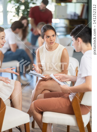 Two teams debating and discussing with teacher as game host in classroom Two teams debating and discussing with teacher as game host in classroom 141252312