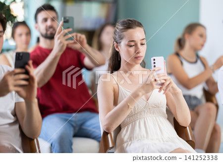 Girl and students point phone camera at widescreen slide presentation screen Girl and students point phone camera at widescreen slide presentation screen 141252338