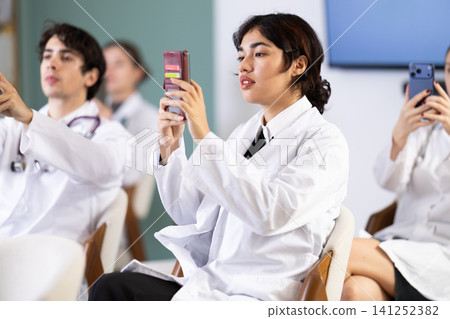 Female doctor scanning QR code with phone in conference hall Female doctor scanning QR code with phone in conference hall 141252382
