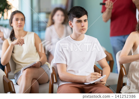 Group of students listening to lecture with teacher in background 141252386