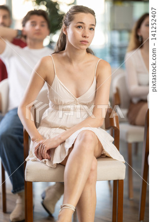 European woman is sitting among a group of people in an audience and listening to a lecture on finance European woman is sitting among a group of people in an audience and listening to a lecture on finance 141252407