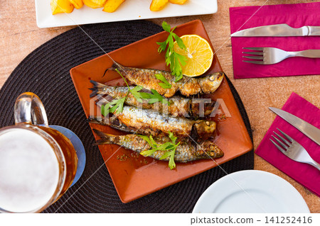 Fried sardines served with slice of lemon Fried sardines served with slice of lemon 141252416