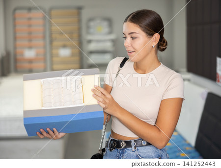 Girl chooses mattress filling in furniture store 141252443